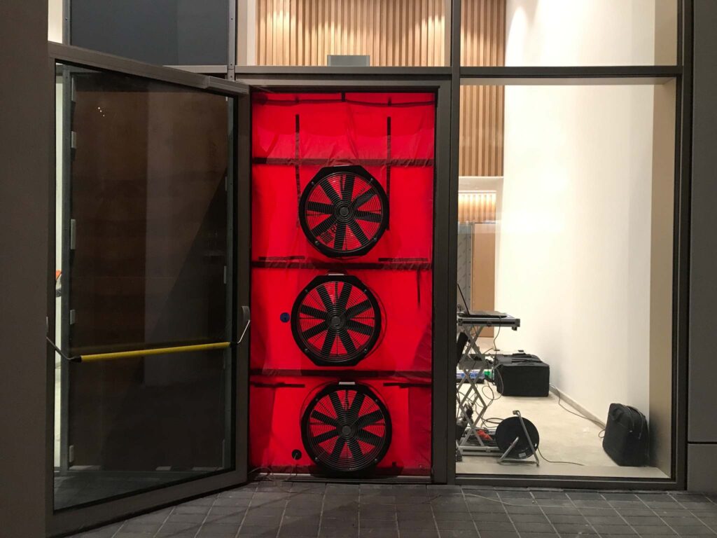 BlowerDoor multi-fan luchtdichtheidstest in entree van utiliteitsgebouw voor nauwkeurige meting van luchtlekken met apparatuur van Blowertechnic