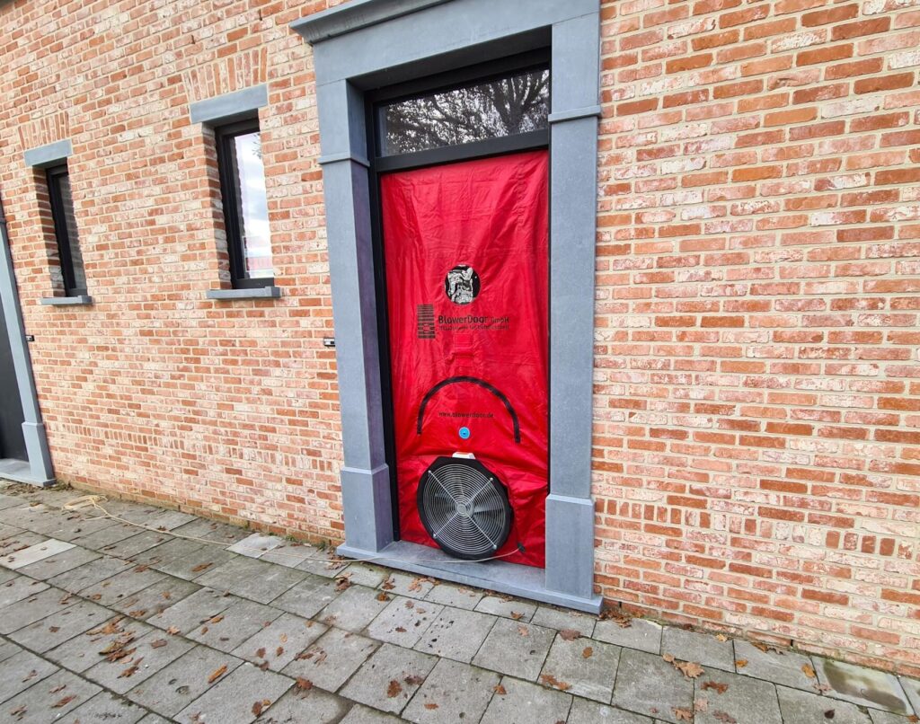 BlowerDoor test bij woninggevel met ventilator in deuropening voor luchtdichtheidsmeting en energieprestatie controle door Blowertechniek