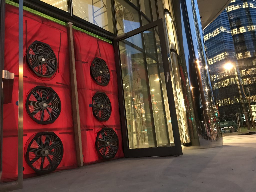 BlowerDoor meetopstelling met meerdere ventilatoren in deuropening van modern kantoorgebouw voor luchtdichtheidstest